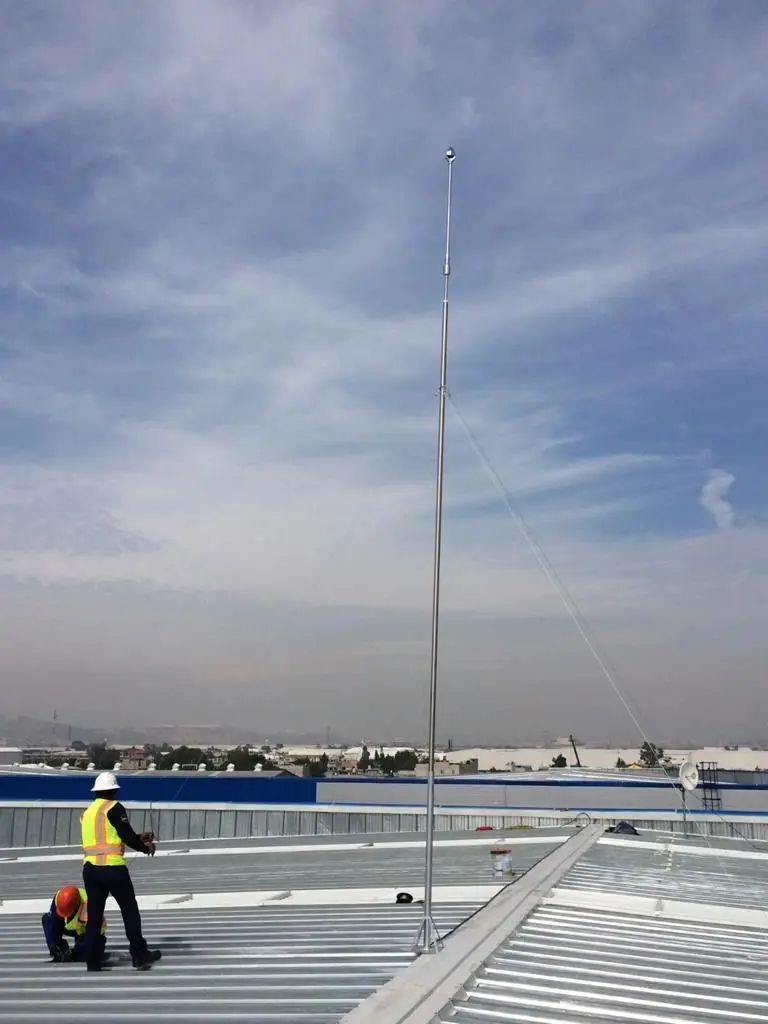 Técnicos de Inter Pararrayos levantando un mástil con retenidas en la lámina de una nave
